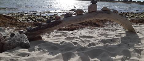Une plage de sable avec une structure en bois et des rochers.