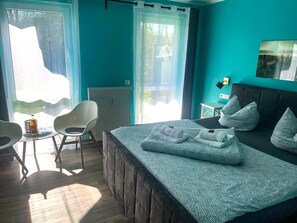 A bedroom with a bed, two chairs, a small table, and a radiator.