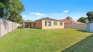 A single-story house with a covered patio, a fenced backyard, and a brick exterior.