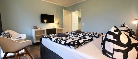 A bedroom with a bed, a chair, a TV, and a wardrobe.