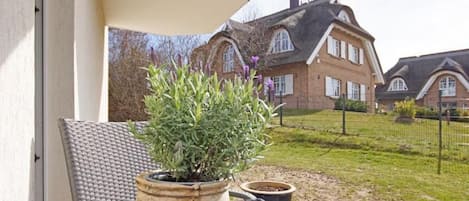 A potted plant on an outdoor table with a view of a house in the background.