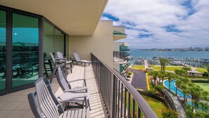 Een balkon met buitenmeubilair, uitzicht op de jachthaven en een zwembad.