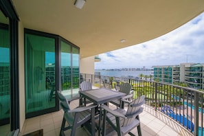 Un balcone con tavolo e sedie, vista su una piscina e un porto turistico.