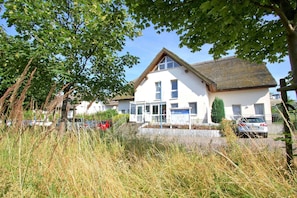 A white building with a sloped roof, a signboard, and a car parked in front. - Doppelzimmer 28 - Strandhaus Mönchgut (Mönchgut)