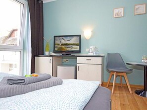 A hotel room with a bed, a desk, a chair, a television, and a window. - Double room 29 - Strandhaus Mönchgut Bed & Breakfast Lobbe (Mönchgut)