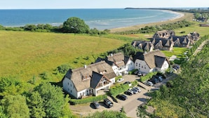 A coastal village with thatched-roof cottages, a parking area, and a view of the sea. - Doppelzimmer 33 - Strandhaus Mönchgut (Mönchgut)