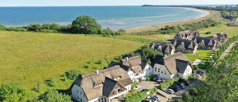 A coastal village with thatched-roof cottages, a parking area, and a view of the sea.