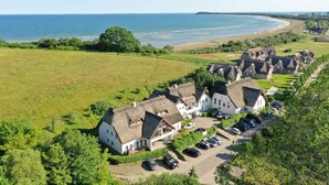 A coastal village with thatched-roof cottages, a parking area, and a view of the sea. - Double room 35 - Strandhaus Mönchgut Bed & Breakfast Lobbe (Mönchgut)
