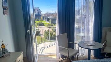 Una habitación con balcón, una silla, una mesa y una cama.