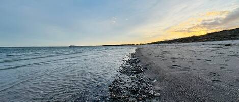 A beach with pebbles and a calm sea.