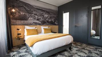 Un dormitorio moderno con una cama grande, un cabecero con un mural, una lámpara de noche y una alfombra estampada.