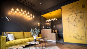 A modern hotel lobby with a yellow sofa, a wooden coffee table, and a map on the wall. - L'Hôtel & Spa  Ribeauvillé (Ribeauvillé)