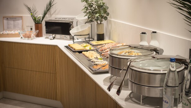A buffet setup with various food items, a microwave, and a plant. - L'Hôtel & Spa  Ribeauvillé (Ribeauvillé)