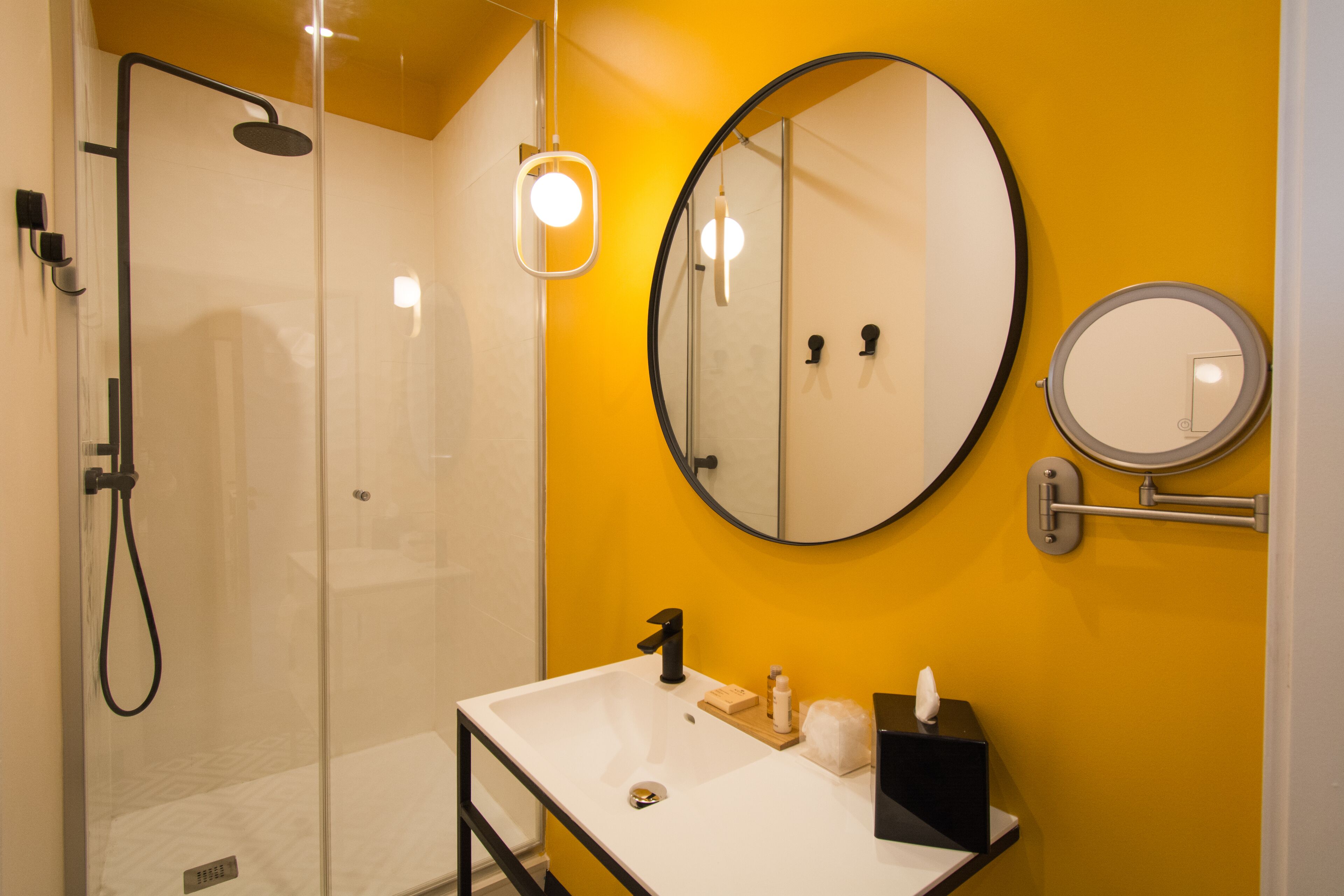 A modern bathroom with a glass-enclosed shower, a white sink, and two mirrors.
