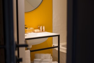 Un baño con un lavamanos blanco, paredes amarillas y una bañera.