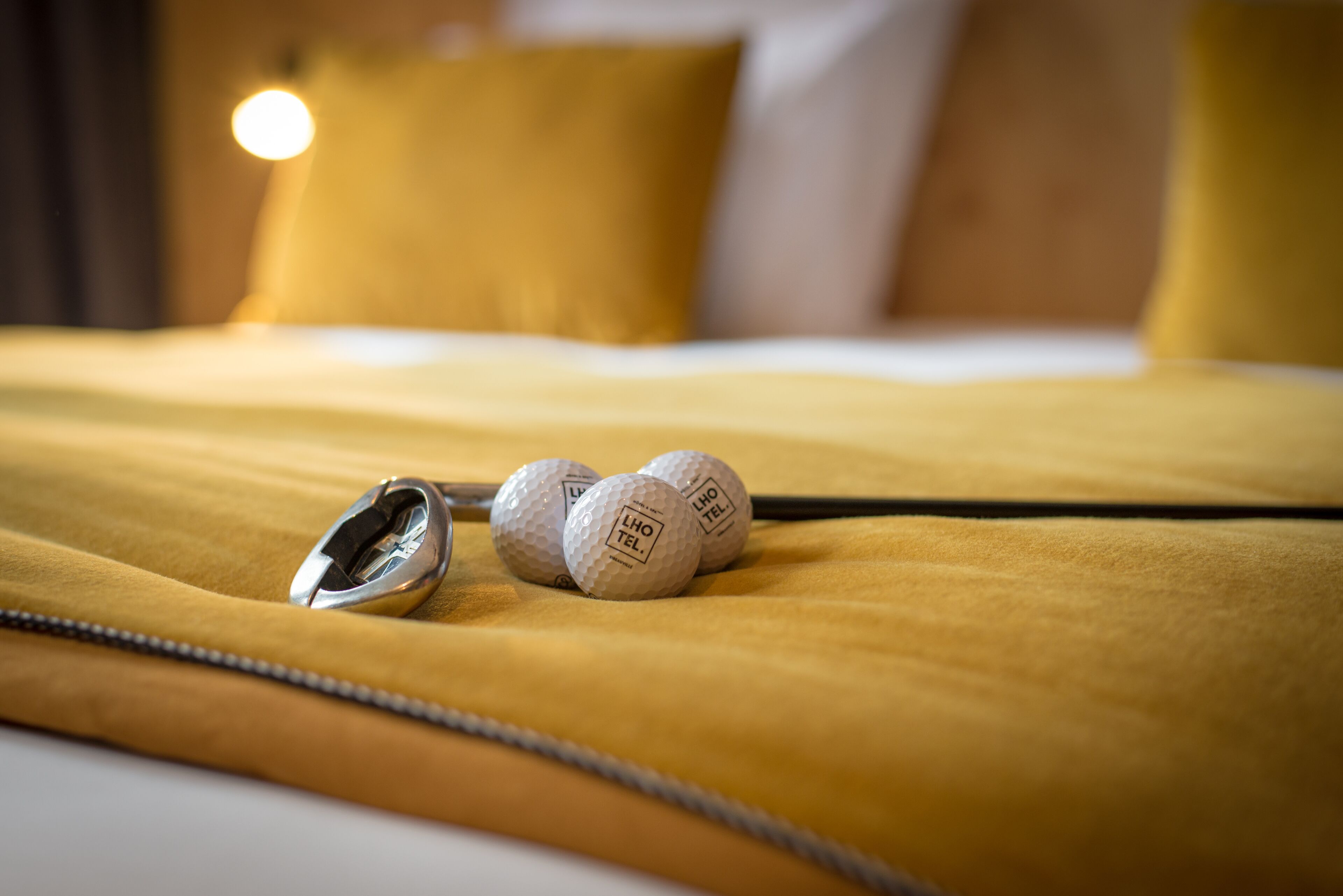 A bed with a yellow bedspread, a zipper, and three golf balls on it.
