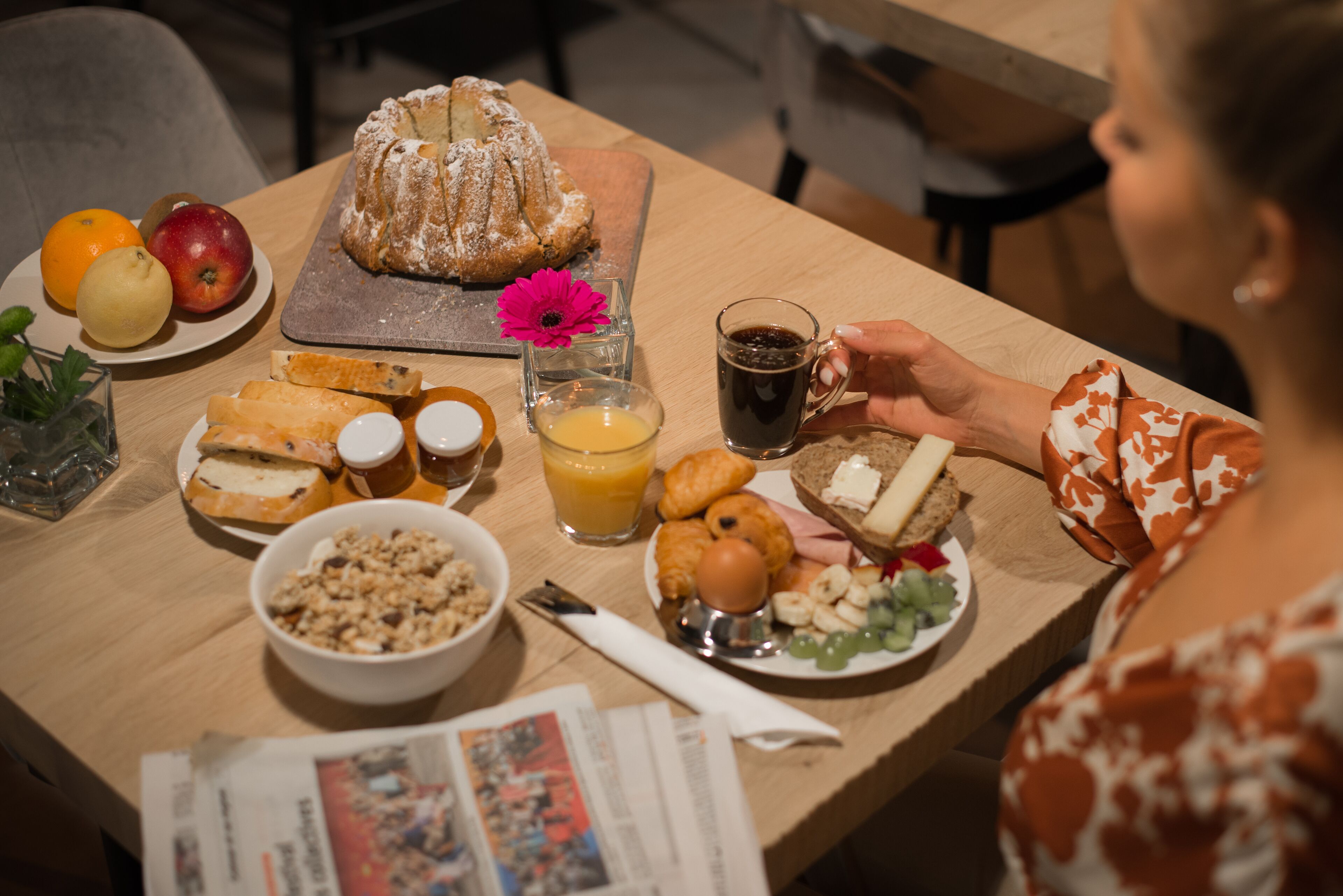 A breakfast table with various food items, including bread, fruits, and a beverage.