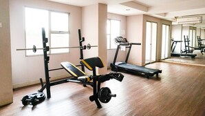 Une salle de sport équipée de matériel d’exercice, dotée de grandes fenêtres et d’un plancher en bois.