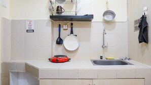 Une cuisine équipée d’un évier, d’un égouttoir, d’une cuisinière et d’un porte-casseroles suspendu.