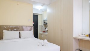 Une chambre d’hôtel avec un lit, un petit bureau et une armoire.