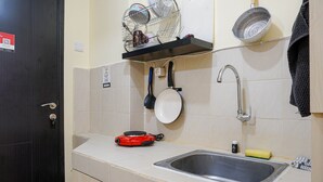 Une cuisine équipée d’un évier, d’un égouttoir, d’une poêle et d’une cuisinière électrique rouge.