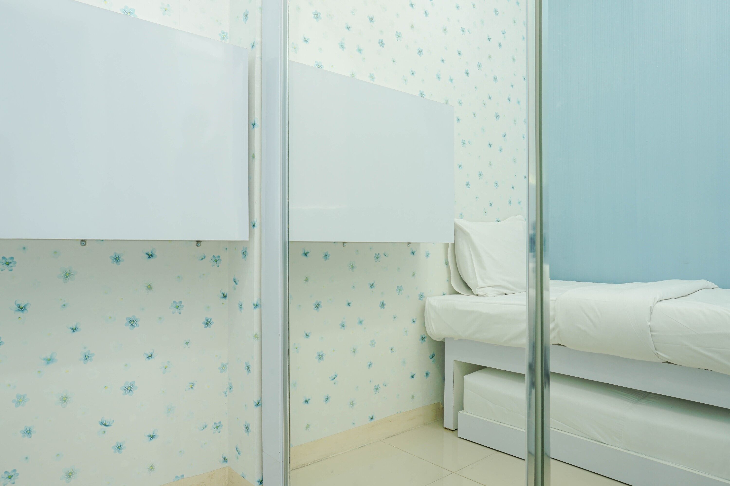 A bedroom with a bed, a wardrobe, and a glass partition.