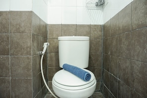 Une salle de bain équipée de toilettes, d’une serviette et d’un flexible de douche.