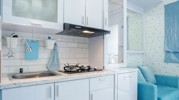 Una cocina moderna con armarios blancos, una estufa a gas y una toalla azul colgada en la pared.