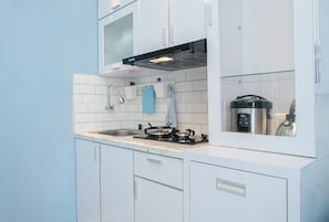 Une cuisine moderne avec des meubles blancs, une cuisinière à gaz, un four encastré et un four à micro-ondes.