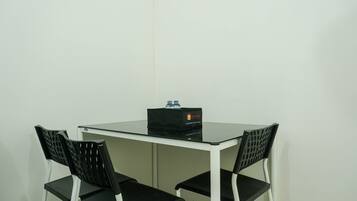 A small, white table with a black bag on top.