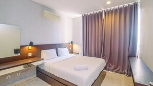 Una habitación de hotel con una cama grande, una mesita de noche, un espejo y una ventana con cortinas.