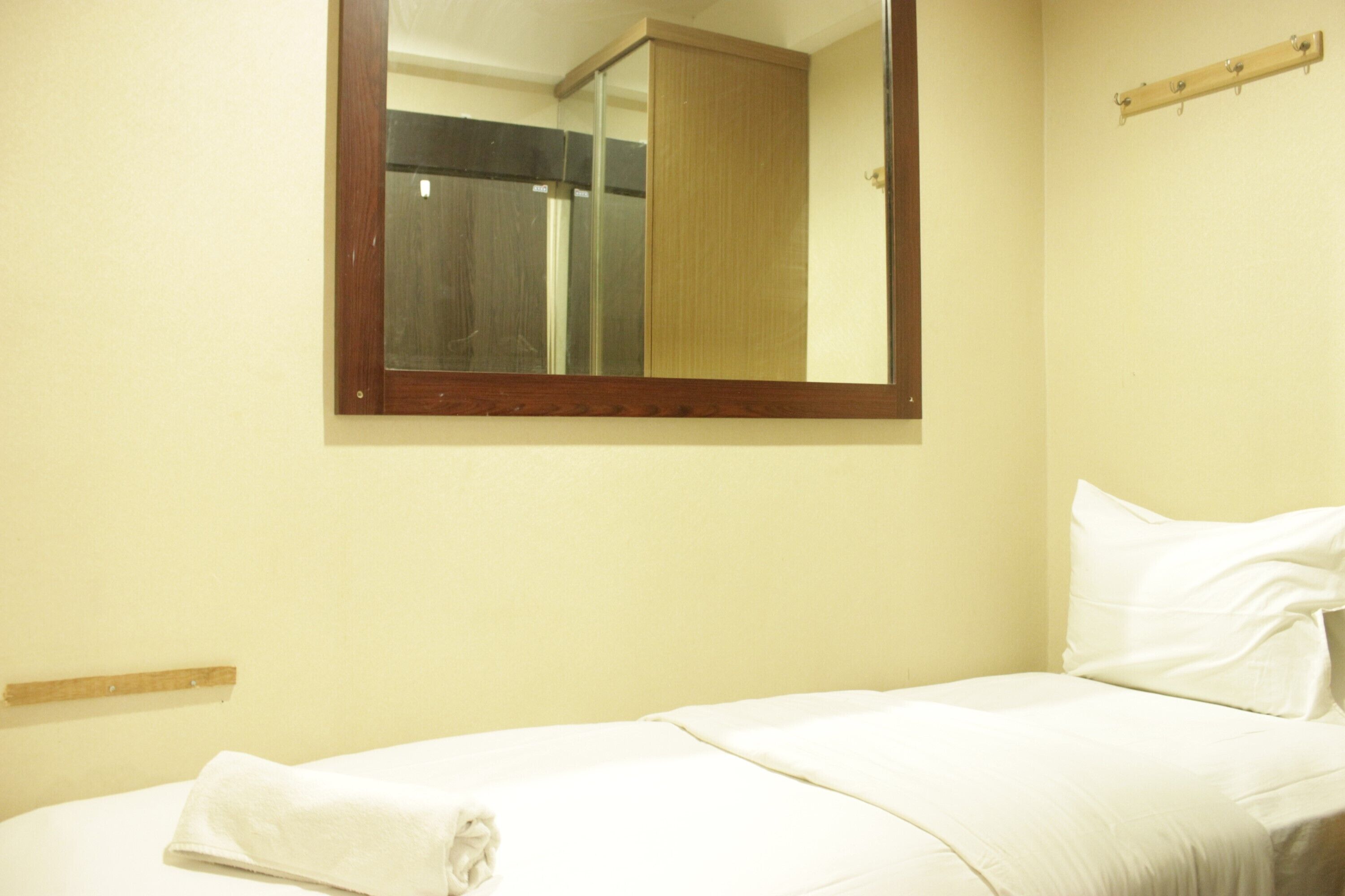 Una habitación de hotel con una cama, un espejo grande y una repisa de madera.