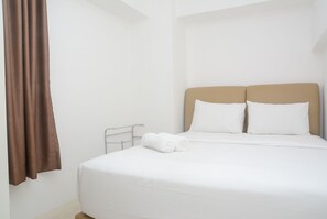 Cama bem arrumada com roupa de cama branca e duas almofadas, cortina marrom à esquerda e estrutura de cama de metal.