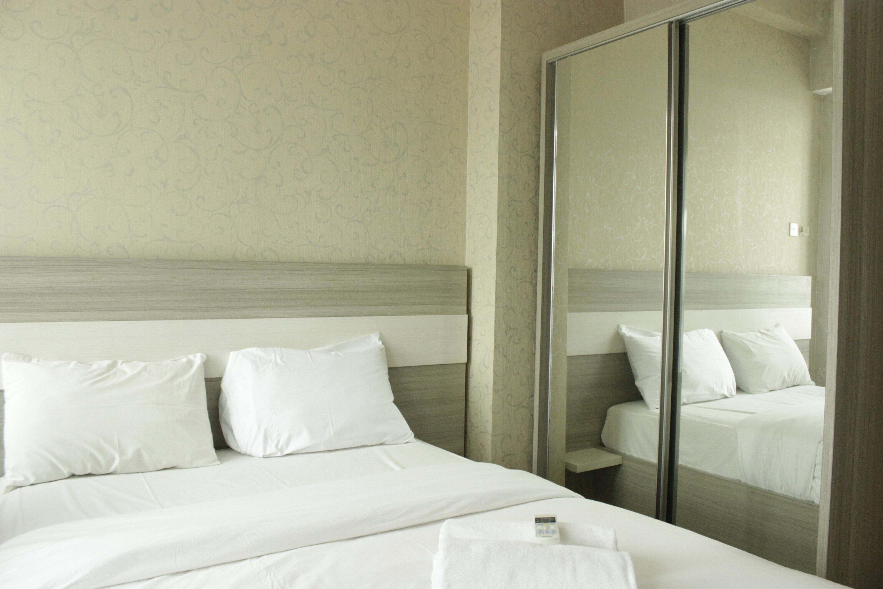 Una habitación de hotel con una cama grande, un espejo y un armario.