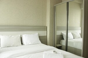 Una habitación de hotel con una cama grande, un espejo y un armario.