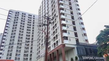 Um edifício alto com várias varandas e um andar térreo comercial.