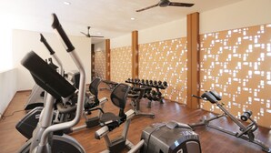 A gym with various exercise equipment, including treadmills, stationary bikes, and weight machines. - Elegant and Relaxing 1BR Asatti Apartment BSD (Pagedangan)