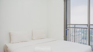 A minimalist bedroom with a large bed, two pillows, and a neatly folded towel. - Fully Furnished with Comfortable Design 2BR Apartment Springwood Residence (Tangerang)