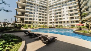 A modern apartment building with a swimming pool and outdoor seating area. - Spacious Studio Room at Gateway Pasteur Apartment near Exit Toll Pasteur (Cimahi)