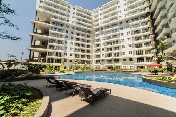 Enjoy the resort's central pool and outdoor seating area with lounge chairs and a table.