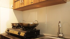 A kitchen with a gas stove, two stainless steel pots, a sink, and wooden cabinets. - Spacious Studio Room at Gateway Pasteur Apartment near Exit Toll Pasteur (Cimahi)