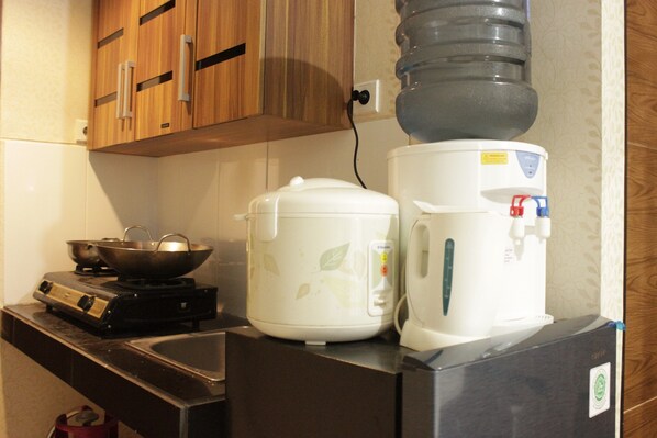 A kitchen with a stove, a rice cooker, and a water dispenser.