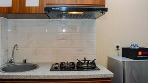 Una cocina con estufa a gas, un lavamanos y una campana extractora.