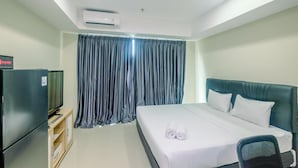 Ein Hotelzimmer mit einem Bett, einem Fernseher, einem Schreibtisch und einer Klimaanlage.