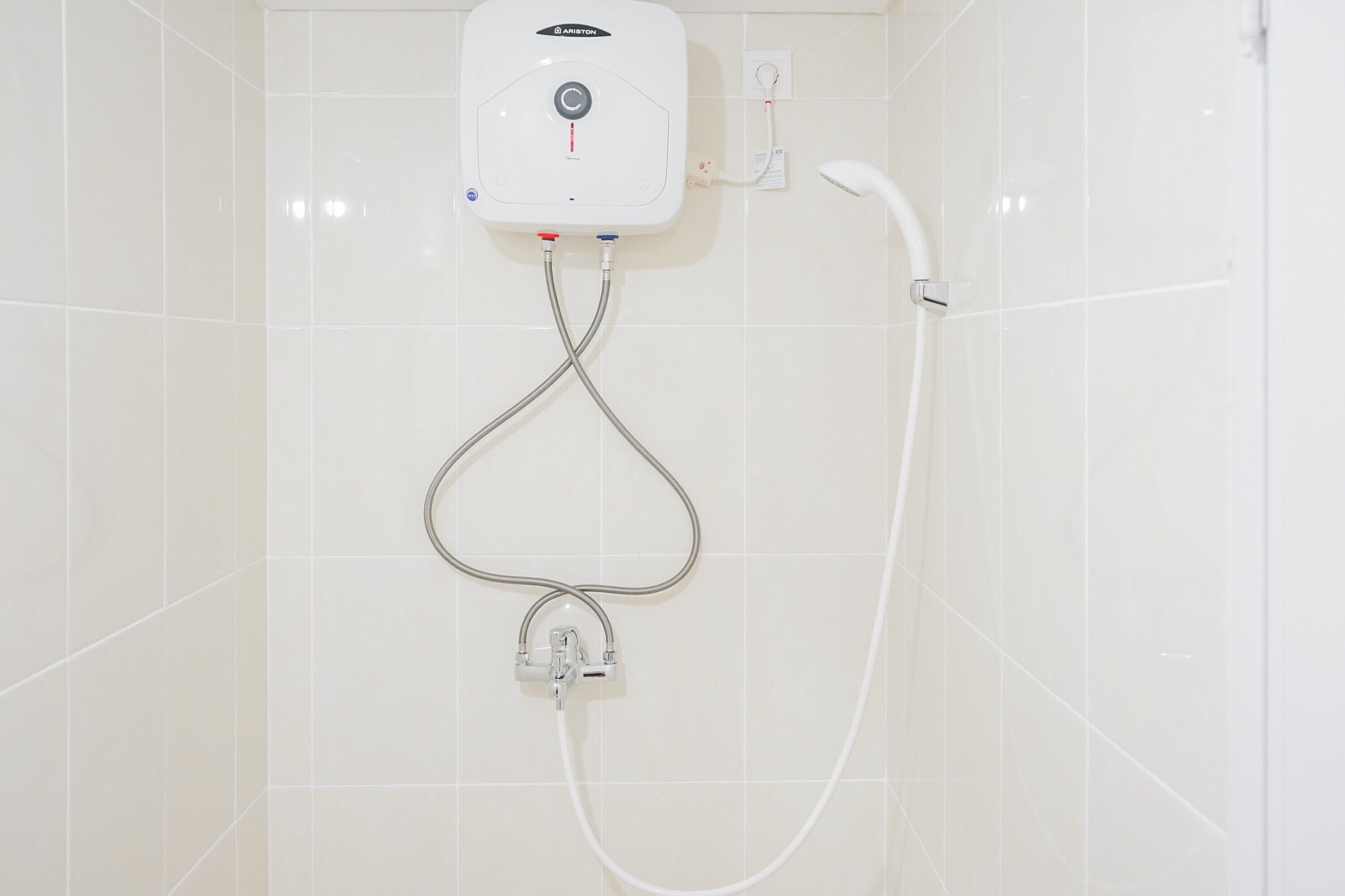 A wall-mounted shower unit with a control panel, a handheld showerhead, and a flexible hose.
