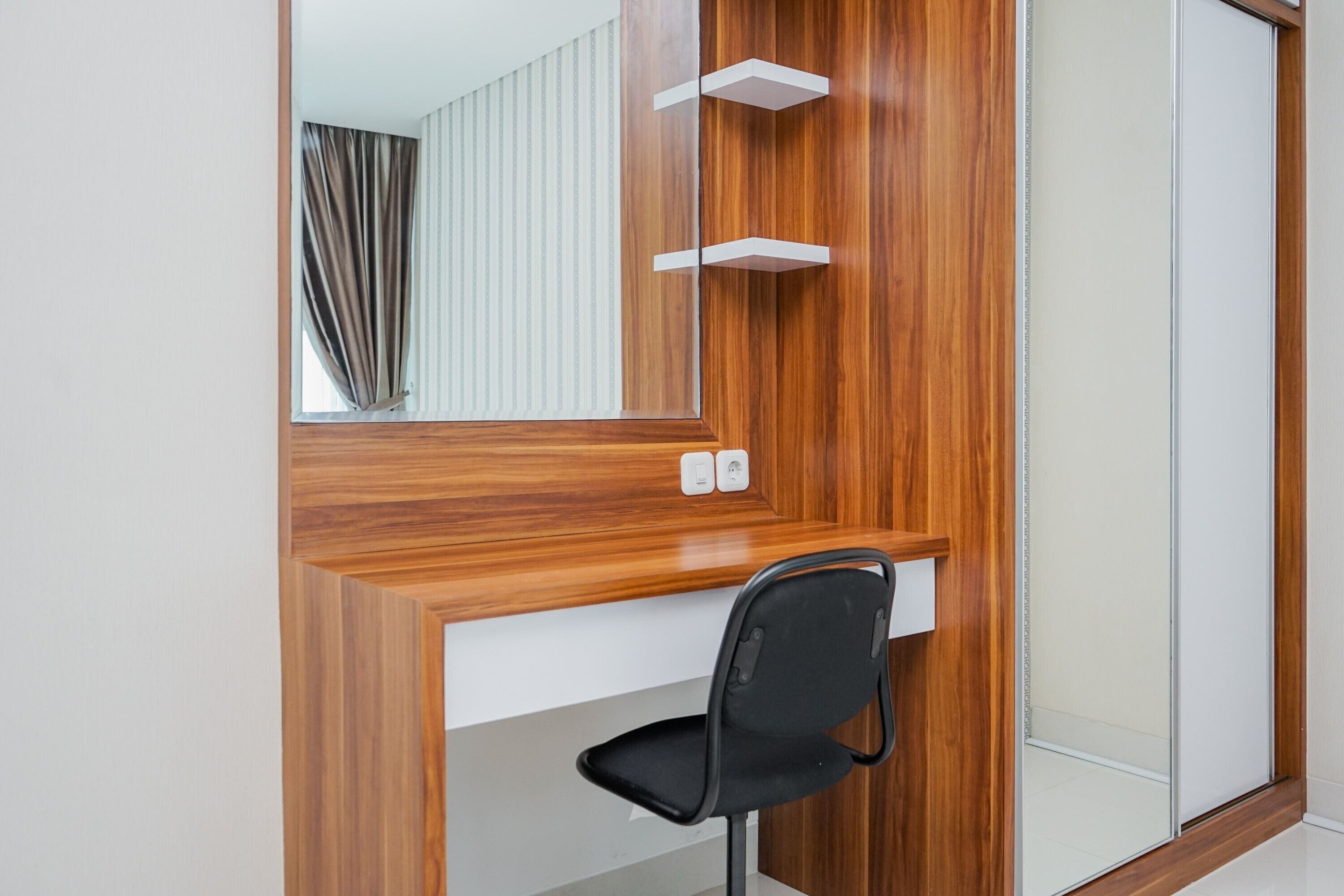 A modern bathroom with a wooden vanity, a black chair, and a mirror.