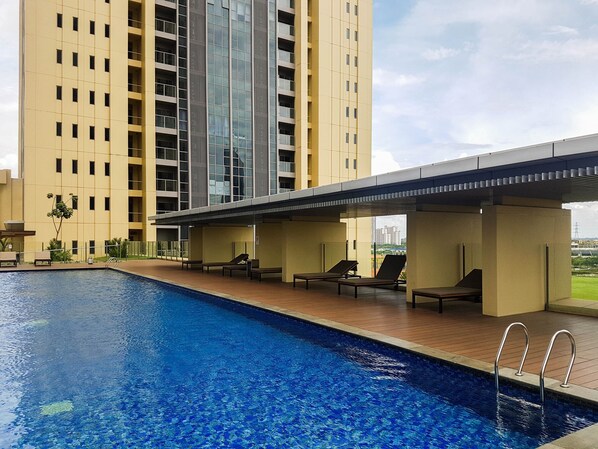Relax by the rooftop pool surrounded by a deck and lounge chairs.