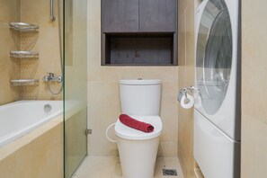 Bathroom features a white toilet, glass-enclosed shower, and a bathtub.