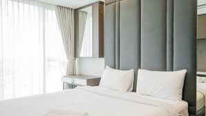 Ein Hotelzimmer mit einem großen Bett, einem Nachttisch, einem Spiegel und Blick auf die Stadt.