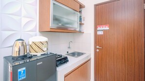 A compact kitchenette with a built-in stove, a sink, and wooden cabinets.